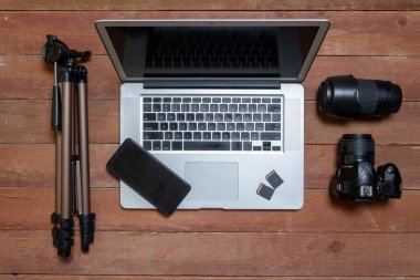 top view of photographer's desk with photographic equipment, with camera, lens, laptop and cell phone