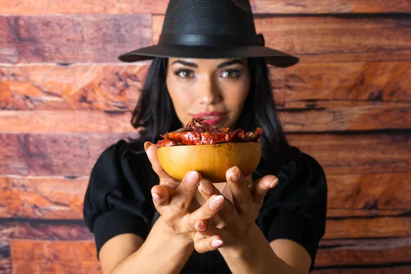 beautiful latin woman cook showing bowl with tree chili peppers. Mexican food