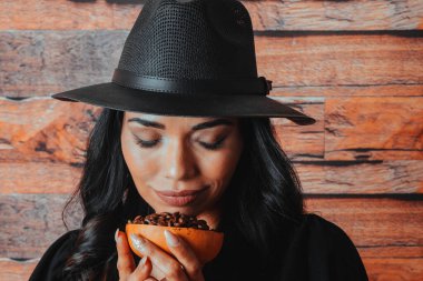 Güzel Latin kadının portresi taze kavrulmuş kahve çekirdeklerini kokluyor.