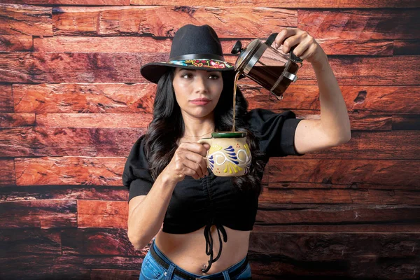 mexican woman with fedora hat serving coffee in mexican cup