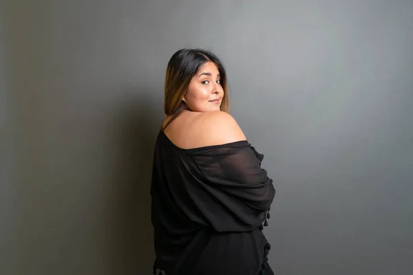 beautiful and tender overweight mexican woman posing sensual on gray background