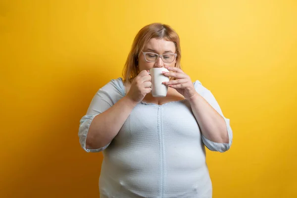 white and chubby young woman drinking cup of coffee. overweight person
