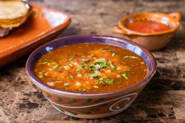 Red birria de res stew with cilantro and onion, served with salsa and tortillas