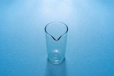 Mavi arka planda boş kimyasal deney şişesi.