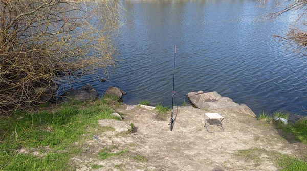 Kıyıdaki balıkçıların yeri. Boş bir sandalye, su deposunun kıyısında bir olta kamışı. Balık istirahatı.