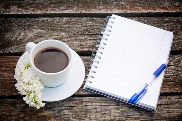 Kaffekopp, anteckningsblock och penna på trä bakgrund — Stockfoto