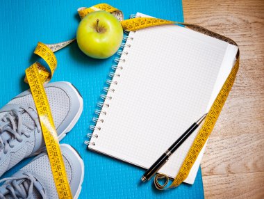 Spor ayakkabı, santimetre, yeşil elma, defter. Kilo verme, sağlıklı yaşam konsepti