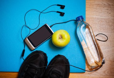 Spor donatımı. Spor ayakkabı, su, elma, akıllı telefon ve kulaklık yoga mat