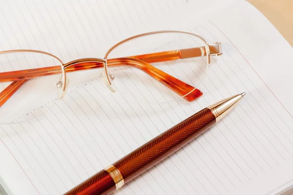 Planificador diario con gafas y bolígrafo sobre la mesa. Enfoque selectivo —  Fotos de Stock