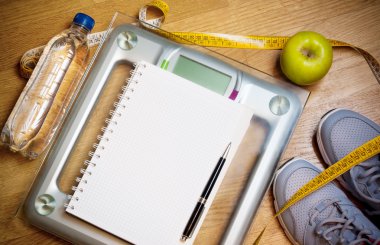 Spor ayakkabı, santimetre, yeşil elma, defter, ölçek, şişe suyu. Sağlıklı yaşam konsepti