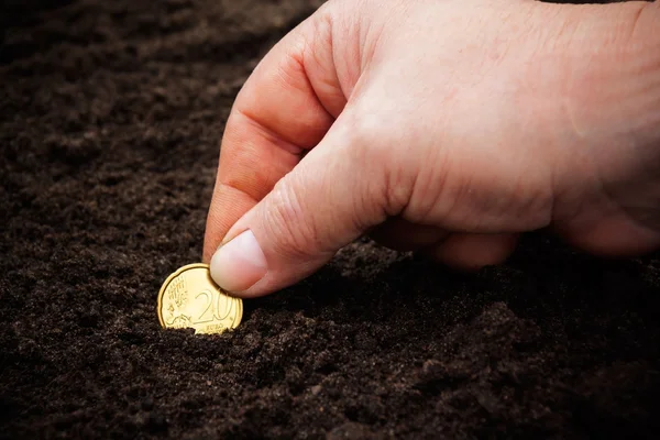 Kobiecej ręki sadzenia monet w glebie. Selektywny fokus — Zdjęcie stockowe