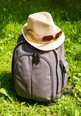 Gri beyaz şapka ve güneş gözlüğü ile sırt çantası çimenlerin üzerinde