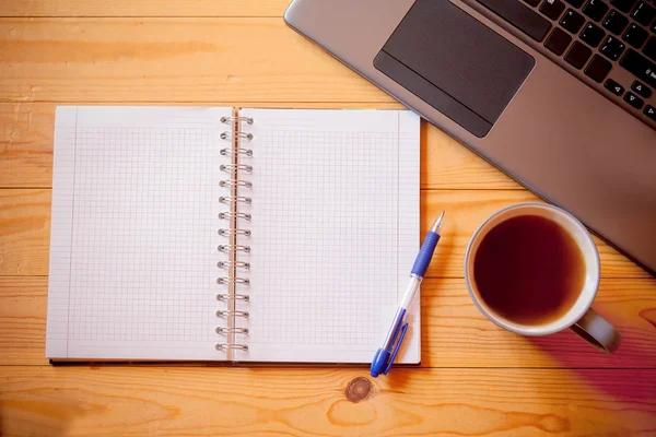 Anteckningsbok, kopp te och laptop på trä bakgrund — Stockfoto