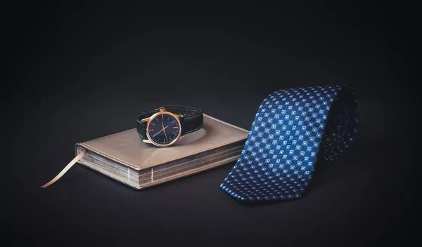 Yuvarlak mavi kravat, günlük ve koyu arkaplanda saat. Seçici odak.