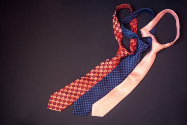 Koyu arkaplanda kırmızı, mavi ve pembe kravatlar. Üst görünüm, alanı kopyala.