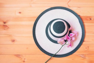 Beyaz yaz şapkası ve ahşap arka planda mor orkide. Yaz ve tropik tatil konsepti. Üst görünüm, alanı kopyala.