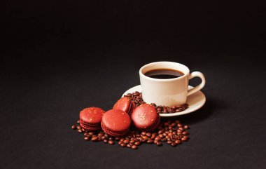 Kahve fincanı, çikolatalı kurabiye ve koyu arkaplanda kahve çekirdekleri. Kopyalama alanı ile göster.