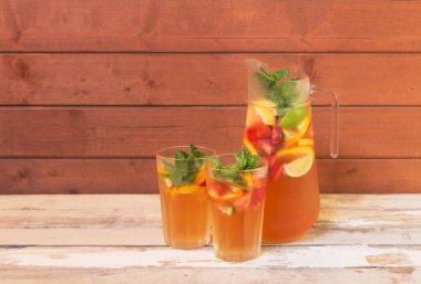 Limonlu soğuk yaz limonatası, sürahi içinde çilek ve limon ve yıllanmış ahşap masada gözlük. Seçici odaklanma. Kopyalama alanı ile göster.