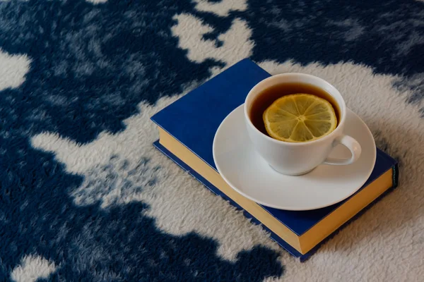 Taza de té con limón y libro sobre la manta —  Fotos de Stock