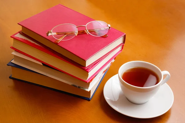 Tazza di tè, bicchieri e pile di libri — Foto Stock