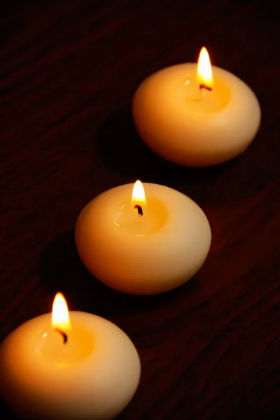 Tres velas sobre una mesa de madera oscura . —  Fotos de Stock