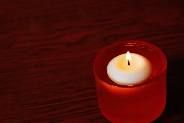 Einzelkerze in orangefarbenem Glasleuchter auf einem dunklen Holztisch — Stockfoto