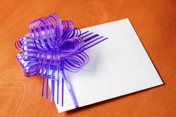 Nahaufnahme einer Notizkarte mit violetter Schleife auf hölzernem Hintergrund — Stockfoto