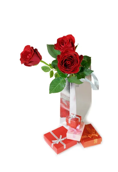 Τρία κόκκινα τριαντάφυλλα σε μια ασημένια δώρο τσάντα και κουτιά δώρου σε λευκό bac — Φωτογραφία Αρχείου