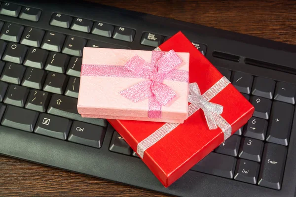 在线购物公司在计算机键盘上的红色和粉色的礼品盒 — 图库照片