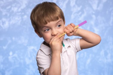 Küçük çocuk dişlerini bambu bir diş fırçasıyla banyoda mavi dokuda fırçalıyor. yatay fotoğraf. Ekolojik olarak temiz. Sabah hijyen konsepti.