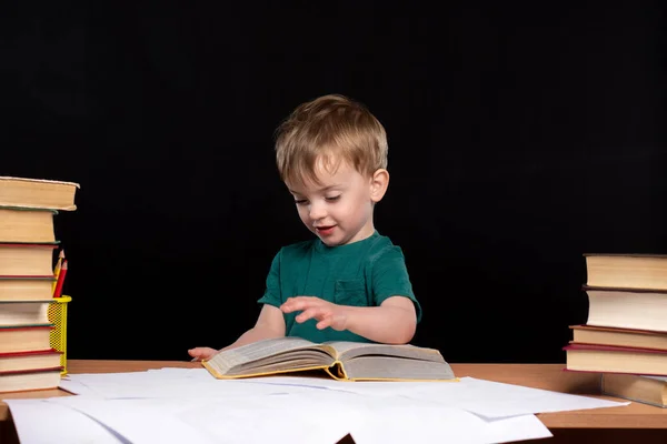 Ein Kleines Kind Europäischen Aussehens Liest Tisch Vor Schwarzem Hintergrund — Stockfoto