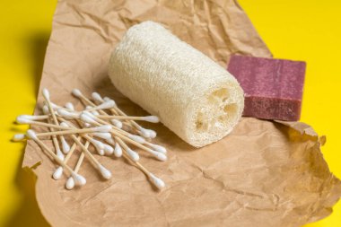 Bambu kulak çubukları, lif ve el yapımı sabun sarı arka plandaki el yapımı kağıdın üzerinde duruyor. mesaj için yer. Çevre dostu. Hijyen ürünleri