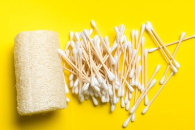Sarı arka planda bambu kulak çubukları ve banyo lifi. Doğal hijyen ürünleri. Sürdürülebilir yaşam tarzı. Sıfır atık.