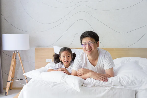 Happy asiatiska familj far och dotter leende på sängen — Stockfoto