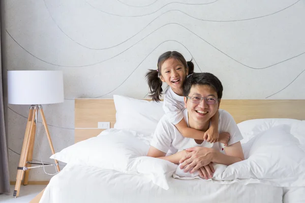 Happy asiatiska familj far och dotter leende på sängen — Stockfoto