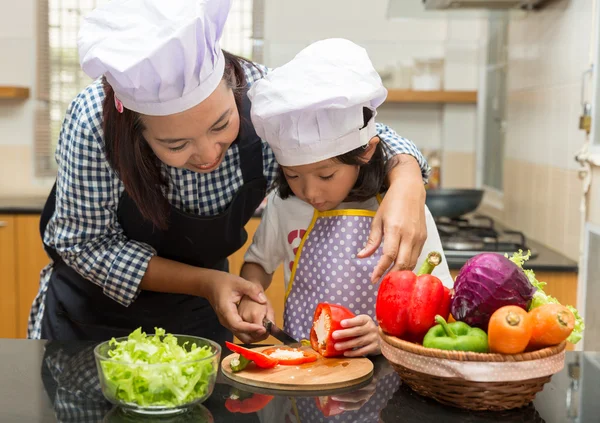 Aziatische moeder onderwijs dochter salade maken in de keuken, koken concept van gelukkig Aziatische klein meisje en moeder maken salade Stockfoto