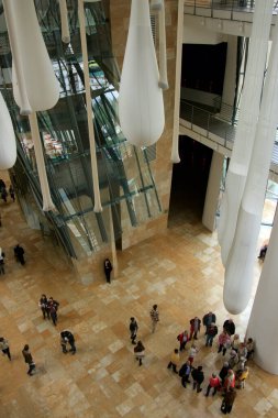 29 Nisan 2014 'te Bilbao Turist Rehberi, Guggenheim Müzesi' nin büyük iç kesimlerindeki ziyaretçileri kuş bakışı lobide açıklıyor..