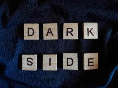 Siyah bir arka planda, durumun olumsuz tarafını sembolize eden ahşap harflerden yapılmış bir yazı var..