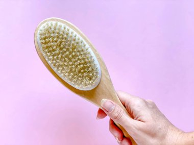 Kuru anti-selülit masajı için kabzalı fırça ya da pembe renkli bir kızın elini fırçalamak. Güzellik konsepti