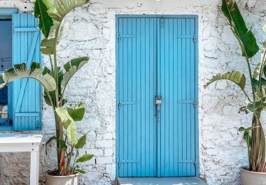 Pencere ve kapıların beyaz mavi süslemesi. Şehrin eski görünümlü beyaz çitlerine karşı açılan parlak mavi bir kapı..