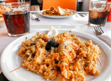 Restorandaki masada karides ve midyeyle pişirilmiş bir İspanyol yemeği var. Restoran menüsü veya İspanyol yemekleri üzerine makaleler