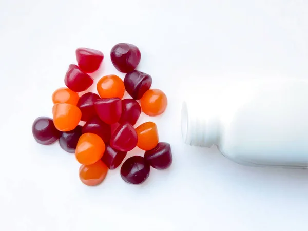 Kırmızı, turuncu ve mor multivitamin sakızları beyaz arka planda izole edilmiş. Sağlıklı yaşam tarzı kavramı.
