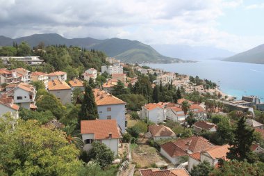 Turuncu kiremit çatılı evlerin üst manzarası gök mavisi deniz suyunun ve güzel dağların arka planına karşı. Karadağ 'ın fotoğrafçılığı. Seyahat kavramı.