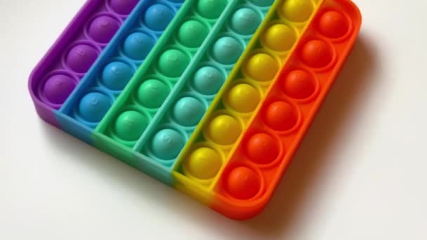 Nahaufnahme Kamerabewegung in der Nähe von Regenbogen-Antistress-Spielzeug zum Schieben mit den Fingern für Kinder — Stockvideo