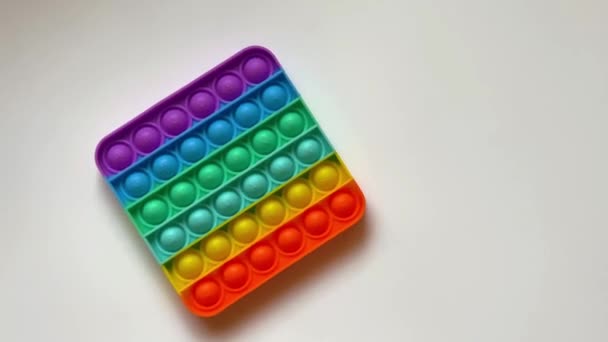 Nahaufnahme Kamerabewegung in der Nähe von Regenbogen-Antistress-Spielzeug zum Schieben mit den Fingern für Kinder — Stockvideo