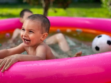 Güneşli yaz havasında havuz başında şişme bir çocuk.