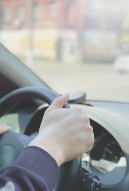 Şehir manzarasının önünden geçen bir adam araba kullanıyor.