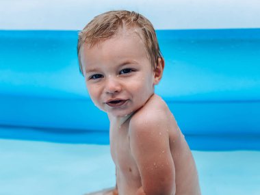 Güneşli yaz havasında havuz başında şişme bir çocuk.