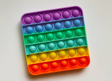 Çocuklar için gökkuşağı anti-stresli parmak itme oyuncağı beyaz arka planda izole edilmiş.