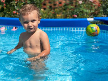 Güneşli yaz havasında havuz başında şişme bir çocuk.